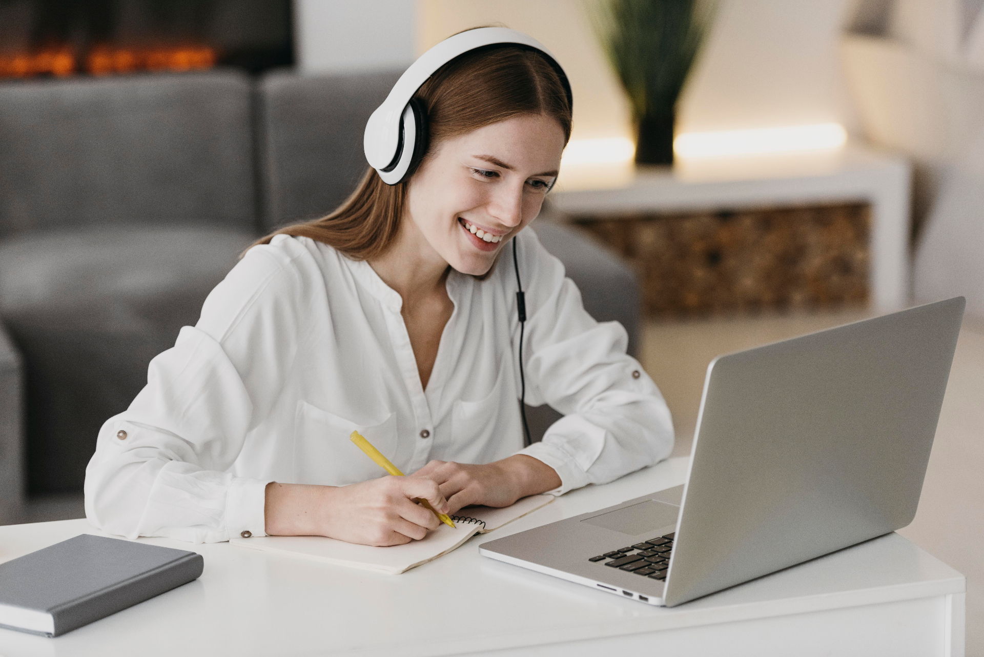 Student smiling while learning online with headphones and a laptop
